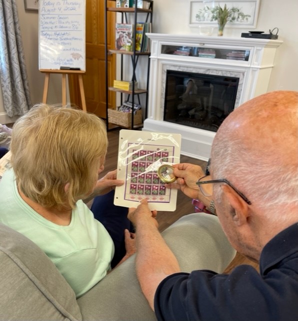 Seniors examining a sheet of stamps with a magnifier